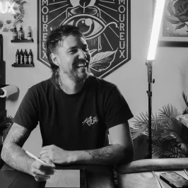 tatoueur assis devant mur d’affiches